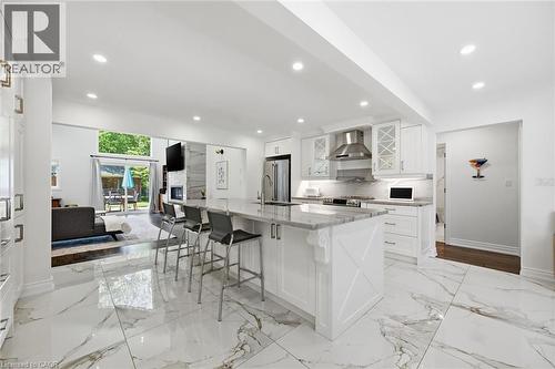 Spacious open-concept kitchen featuring a large center island with seating, white shaker cabinetry, stainless steel appliances, and marble-look tile flooring - 24 Glenwood Crescent, Hamilton, ON - Indoor Photo Showing Kitchen With Upgraded Kitchen