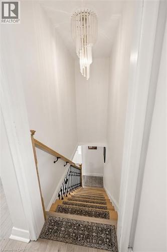 Modern spiral chandelier illuminating a staircase with wood-finish treads, black wrought iron balusters, and a natural wood handrail - 786 S Stirling Avenue S, Kitchener, ON - Indoor Photo Showing Other Room