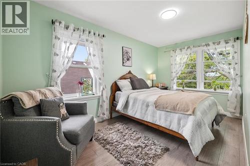 Spacious room with two large windows, light-tone wood-finish flooring, a contemporary flush-mount ceiling light fixture, and walls painted in a soft green hue - 786 S Stirling Avenue S, Kitchener, ON - Indoor Photo Showing Bedroom