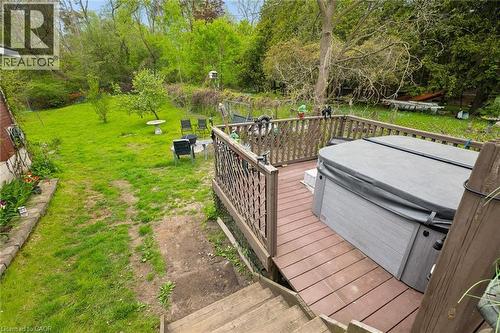 Multi-level deck with a built-in spa, wood-finish railing, and steps descending to a grassy yard with mature trees - 786 S Stirling Avenue S, Kitchener, ON - Outdoor