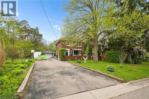 Brick residence featuring a paved driveway, front lawn with mature trees, and a detached garage - 786 S Stirling Avenue S, Kitchener, ON - Outdoor