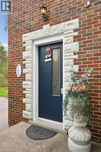 Brick exterior featuring a dark blue entry door with a rectangular frosted glass insert, framed by decorative stone trim - 786 S Stirling Avenue S, Kitchener, ON - Outdoor