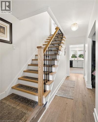 Staircase featuring wood-finish treads, white risers, and a wood-finish handrail with black iron balusters - 786 S Stirling Avenue S, Kitchener, ON - Indoor Photo Showing Other Room