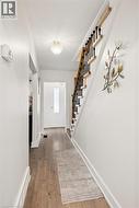 Entry hallway with wood-finish flooring, white baseboards, and a contemporary flush-mount ceiling fixture - 