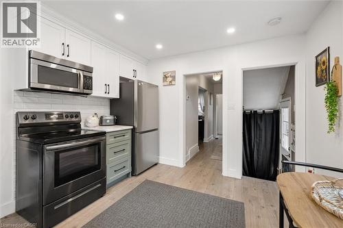 Kitchen featuring stainless steel appliances, white cabinetry, a subway tile backsplash, light wood-finish flooring, and recessed lighting - 786 S Stirling Avenue S, Kitchener, ON - Indoor Photo Showing Kitchen