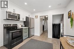 Kitchen featuring stainless steel appliances, white cabinetry, a subway tile backsplash, light wood-finish flooring, and recessed lighting - 