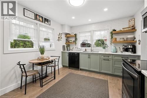 Kitchen featuring light wood-finish flooring, white subway tile backsplash, and sage green cabinetry - 786 S Stirling Avenue S, Kitchener, ON - Indoor