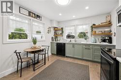 Kitchen featuring light wood-finish flooring, white subway tile backsplash, and sage green cabinetry - 