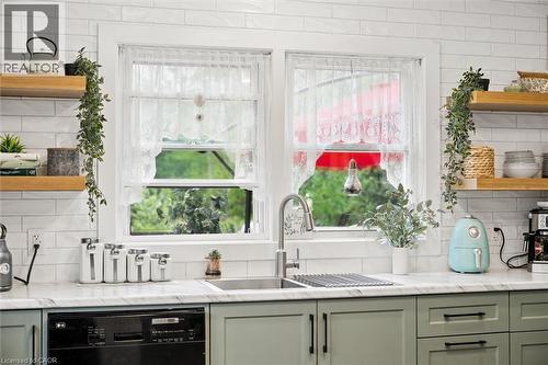 Kitchen featuring a dual-basin stainless steel sink with a gooseneck faucet, light green cabinetry with dark hardware, and a white subway tile backsplash - 786 S Stirling Avenue S, Kitchener, ON - Indoor Photo Showing Kitchen