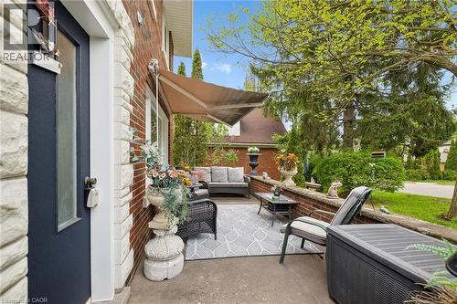 Inviting outdoor patio featuring a retractable awning, concrete flooring, and a brick knee wall - 786 S Stirling Avenue S, Kitchener, ON - Outdoor With Deck Patio Veranda With Exterior