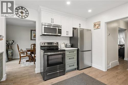 Modern kitchen featuring white shaker cabinetry, stainless steel appliances including a microwave, range, and refrigerator, light wood-finish flooring, and a subway tile backsplash - 786 S Stirling Avenue S, Kitchener, ON - Indoor Photo Showing Kitchen