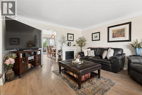 Living area featuring light wood-finish flooring, white crown molding, and a fireplace with a white mantel - 786 S Stirling Avenue S, Kitchener, ON - Indoor Photo Showing Living Room With Fireplace