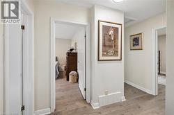 Hallway featuring wood-finish flooring, light-colored walls, white trim, and recessed lighting - 