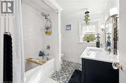 Bathroom featuring a white subway tile shower surround, a white bathtub with chrome fixtures, a dark wood vanity with a white countertop and undermount sink, and patterned floor tiling - 