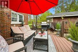 Spacious outdoor deck featuring composite decking, brick exterior wall, and a full-size outdoor umbrella - 