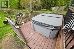 Spacious outdoor deck featuring composite decking, sturdy wood railings, and a built-in hot tub with a protective cover - 