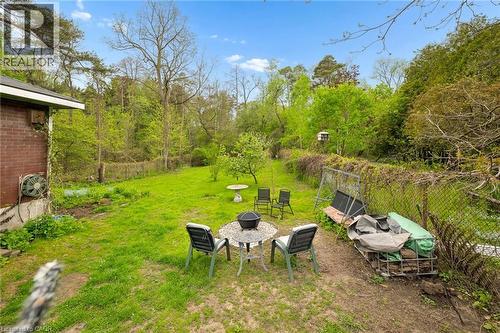 Expansive green lawn surrounded by mature trees, featuring a chain-link fence and a small brick exterior section - 786 S Stirling Avenue S, Kitchener, ON - Outdoor