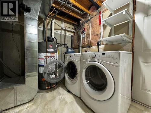 Utility area featuring a water heater, two front-load appliances, a white paneled door, and built-in shelving - 37 Northcliffe Crescent, Cambridge, ON - Indoor Photo Showing Laundry Room
