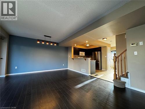 Open-concept living space featuring dark wood-finish flooring, a contemporary linear light fixture, and a kitchen pass-through with a breakfast bar - 37 Northcliffe Crescent, Cambridge, ON - Indoor Photo Showing Other Room