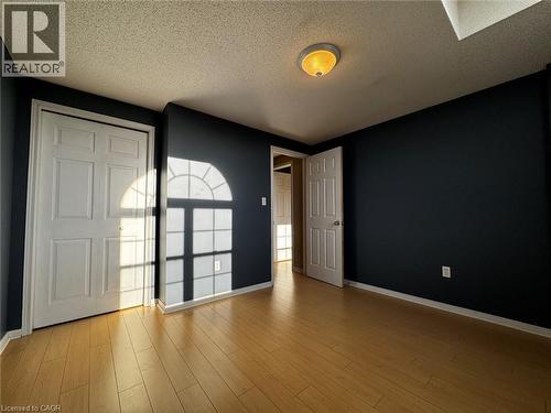 Interior room featuring wood-finish flooring, dark-painted walls, and a textured ceiling - 37 Northcliffe Crescent, Cambridge, ON - Indoor Photo Showing Other Room