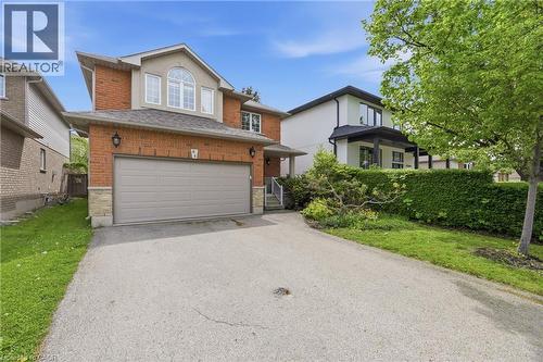 Brick facade residence featuring a two-car garage, upper-level arched window, and a paved driveway - 84 Duncairn Crescent, Hamilton, ON - Outdoor