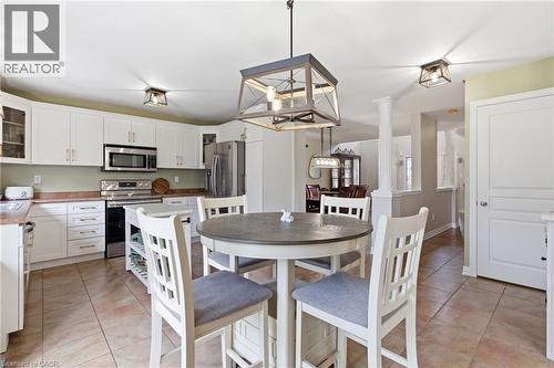 Spacious kitchen featuring white cabinetry, stainless steel appliances, tiled flooring, and a central peninsula with seating - 84 Duncairn Crescent, Hamilton, ON - Indoor Photo Showing Dining Room