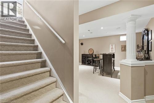 Carpeted staircase with white handrail leading to a lower level featuring a built-in bar area with recessed lighting, a decorative column, and light-toned wall finishes - 84 Duncairn Crescent, Hamilton, ON - Indoor Photo Showing Other Room