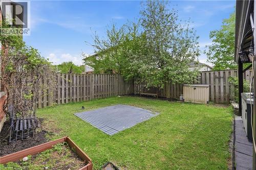 Private backyard featuring a wooden privacy fence, mature trees, green lawn, and a side patio with pavers - 84 Duncairn Crescent, Hamilton, ON - Outdoor With Backyard