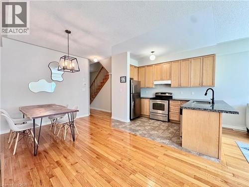 Open-concept living space featuring wood-finish flooring, a kitchen with stainless steel appliances, light wood cabinetry, and a dark granite countertop - 110 Highland Road E Unit# 53, Kitchener, ON - Indoor