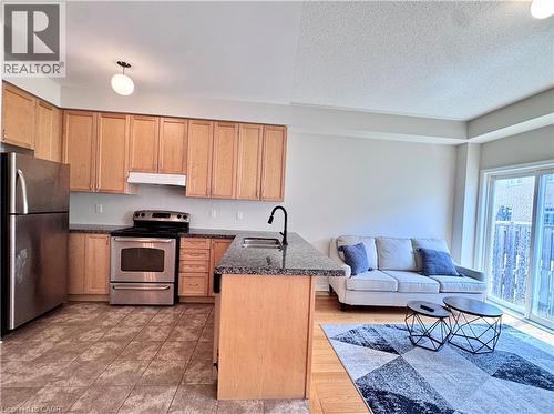 Open-concept kitchen and living area featuring wood cabinetry, stainless steel appliances, and granite-style countertops with an undermount sink - 110 Highland Road E Unit# 53, Kitchener, ON - Indoor Photo Showing Kitchen
