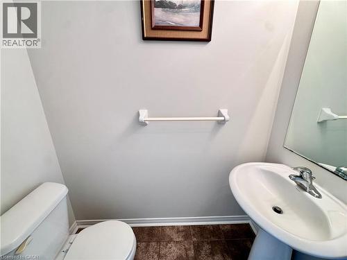 Pedestal sink with chrome faucet, a white toilet, and dark tile flooring - 110 Highland Road E Unit# 53, Kitchener, ON - Indoor Photo Showing Bathroom