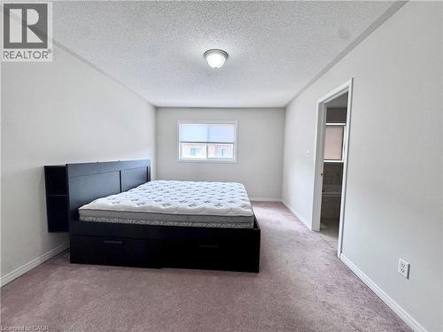 Carpeted room featuring a ceiling-mounted light fixture, a window with a blind, and a doorway opening to an additional space - 110 Highland Road E Unit# 53, Kitchener, ON - Indoor Photo Showing Bedroom