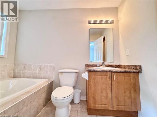Bathroom featuring a built-in tub, tiled surround, and a vanity with a patterned countertop and wood-finish cabinetry - 110 Highland Road E Unit# 53, Kitchener, ON - Indoor Photo Showing Bathroom
