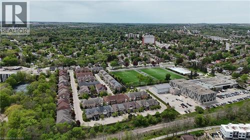 Aerial perspective showcasing a residential development surrounded by mature trees, sports fields, and a large institutional building - 110 Highland Road E Unit# 53, Kitchener, ON - Outdoor With View