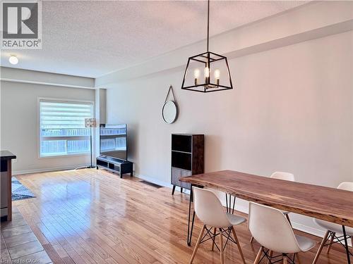 Spacious interior featuring wood-finish flooring, a contemporary black metal framed chandelier, a large window with horizontal blinds, and smooth light-toned walls - 110 Highland Road E Unit# 53, Kitchener, ON - Indoor Photo Showing Dining Room