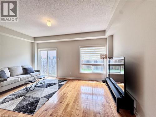 Hardwood flooring throughout a living space featuring a sliding glass door and a rectangular window with blinds - 110 Highland Road E Unit# 53, Kitchener, ON - Indoor Photo Showing Living Room