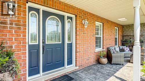 Inviting covered front porch with a dark blue entry door, decorative glass sidelights, and leaded glass transom - 32A Haldimand Trail, Dunnville, ON - Outdoor With Deck Patio Veranda With Exterior