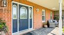 Inviting covered front porch with a dark blue entry door, decorative glass sidelights, and leaded glass transom - 32A Haldimand Trail, Dunnville, ON  - Outdoor With Deck Patio Veranda With Exterior 