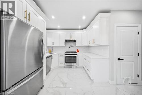 Kitchen with stainless steel appliances, light marble finish floors, white cabinets, recessed lighting, and light stone counters - 273 Stinson Crescent, Hamilton, ON - Indoor Photo Showing Kitchen