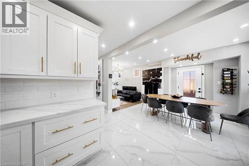 Kitchen featuring open floor plan, white cabinetry, light stone counters, backsplash, and light marble finish floors - 273 Stinson Crescent, Hamilton, ON - Indoor Photo Showing Other Room