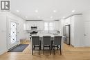 Kitchen with a breakfast bar, stainless steel appliances, white cabinets, a center island, and light wood finished floors - 129 Jackson Street W, Hamilton, ON  - Indoor 