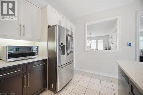 Kitchen featuring white upper cabinetry, dark lower cabinetry, and a full-size stainless steel refrigerator - 58 Doon Creek Street, Kitchener, ON - Indoor Photo Showing Kitchen