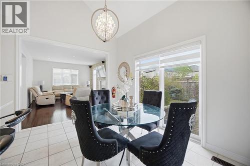 Open-concept living space featuring a dining area with white tile flooring, a contemporary chandelier, and a sliding glass door leading to the backyard - 58 Doon Creek Street, Kitchener, ON - Indoor Photo Showing Dining Room