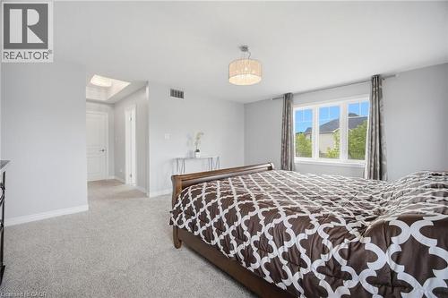 Carpeted bedroom with a three-panel window, a chandelier-style light fixture, and a skylight feature in the entryway - 58 Doon Creek Street, Kitchener, ON - Indoor Photo Showing Bedroom