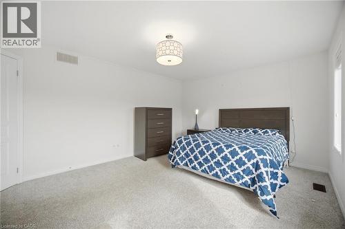 Carpeted room featuring a ceiling light fixture, white walls, and a window providing natural light - 58 Doon Creek Street, Kitchener, ON - Indoor Photo Showing Bedroom