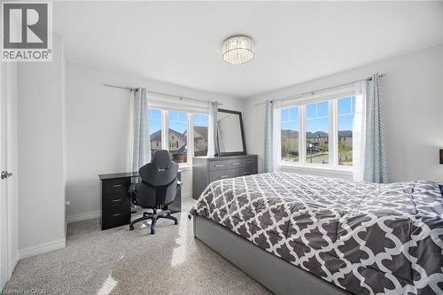 Bright room featuring a large window with multiple panes, light-colored carpeting, and a built-in ceiling light fixture - 58 Doon Creek Street, Kitchener, ON - Indoor Photo Showing Bedroom
