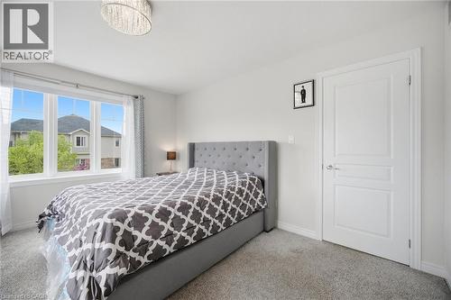Bright room featuring a large window with multiple panes, light gray carpeting, and white walls - 58 Doon Creek Street, Kitchener, ON - Indoor Photo Showing Bedroom