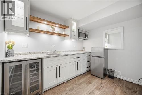 Kitchenette featuring white cabinetry with dark hardware, a stainless steel sink with a modern faucet, and a light-toned speckled countertop - 58 Doon Creek Street, Kitchener, ON - Indoor Photo Showing Kitchen With Upgraded Kitchen