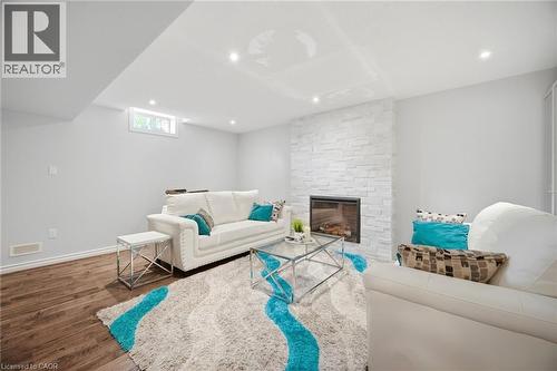 Spacious room featuring a stone-clad fireplace, wood-finish flooring, recessed lighting, and a window - 58 Doon Creek Street, Kitchener, ON - Indoor With Fireplace