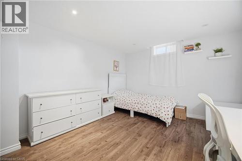 Bedroom featuring wood-finish flooring, white walls, recessed lighting, and a window with white sheer curtain - 58 Doon Creek Street, Kitchener, ON - Indoor Photo Showing Bedroom